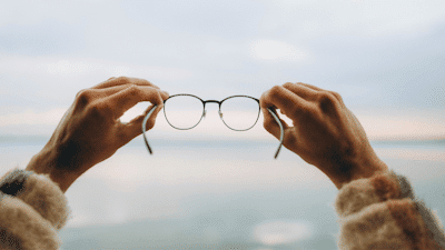 Mains tenant des lunettes en direction de l'horizon, symbolisant la vision et les perspectives